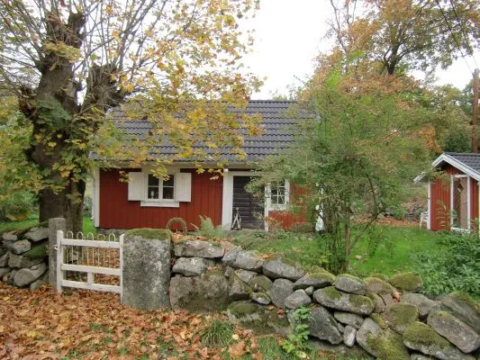 Röd stuga med stenmur och höstfärger i Blekinge